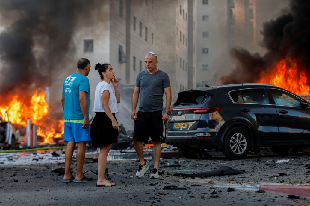 People react near a fire after rockets were launched from the Gaza Strip, in Ashkelon, Israel.