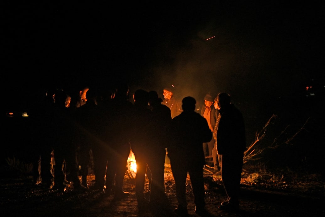 A photograph of refugees from Nagorno-Karabakh gather around a fire to warm themselves after getting stuck in a queue of vehicles on the road leading towards the Armenian border, in Nagorno-Karabakh, September 25, 2023.