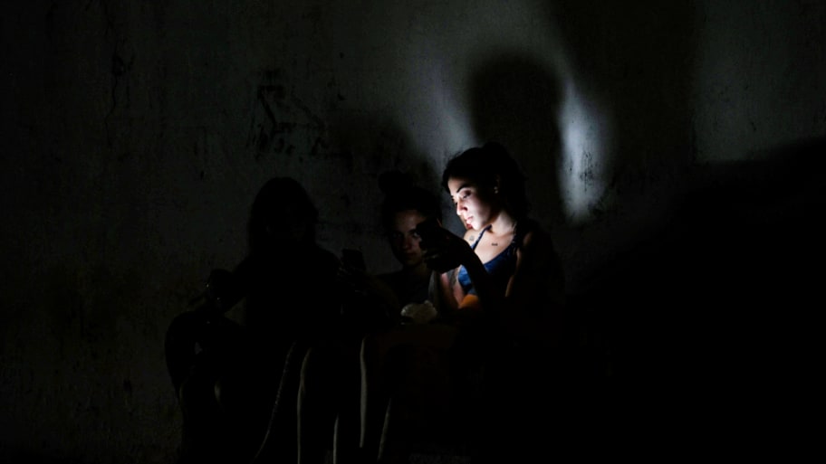 People use their cell phones in a dark street during a blackout in Bauta municipality, Artemisa province, Cuba, on March 18, 2024.