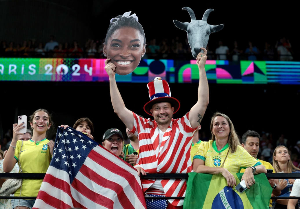 A USA fan holds up a cutout of Simone Biles and a goat’s head