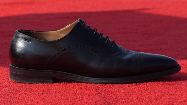 Donald Trump's abandoned black polished Oxford shoe, on a red carpet