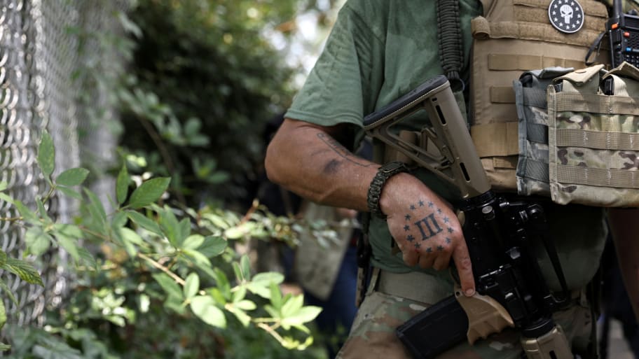 A Three Percent militia logo is seen tattooed on a militia member's hand.