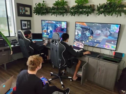 Three men play video games on large screens