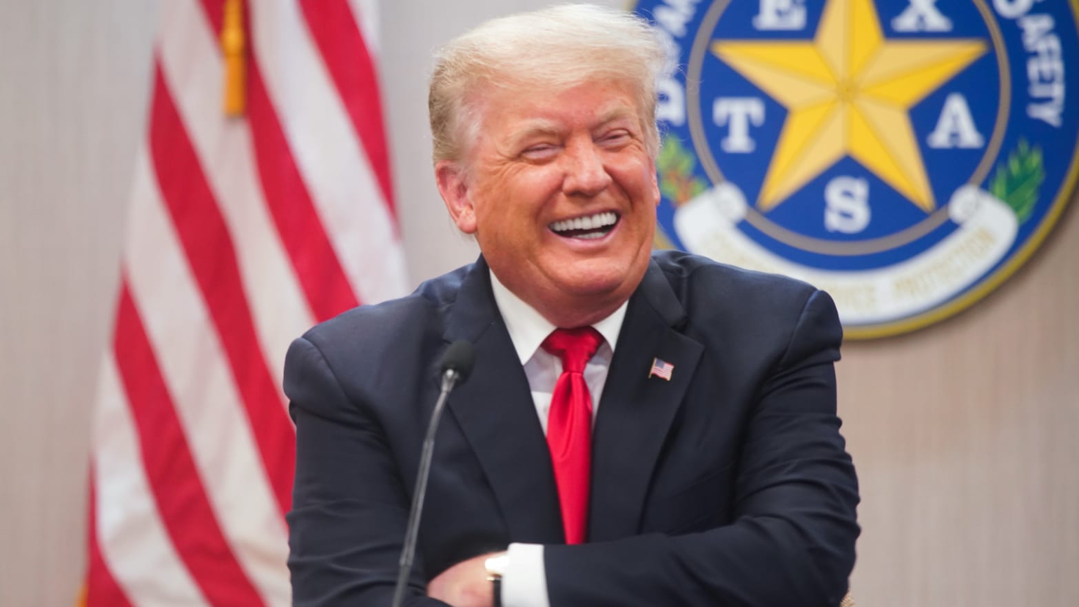 Donald Trump laughs behind a lectern.