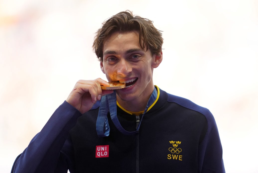 Mondo Duplantis of Sweden celebrates with his gold medal on the podium after winning the men's pole vault competition at the 2024 Olympics.