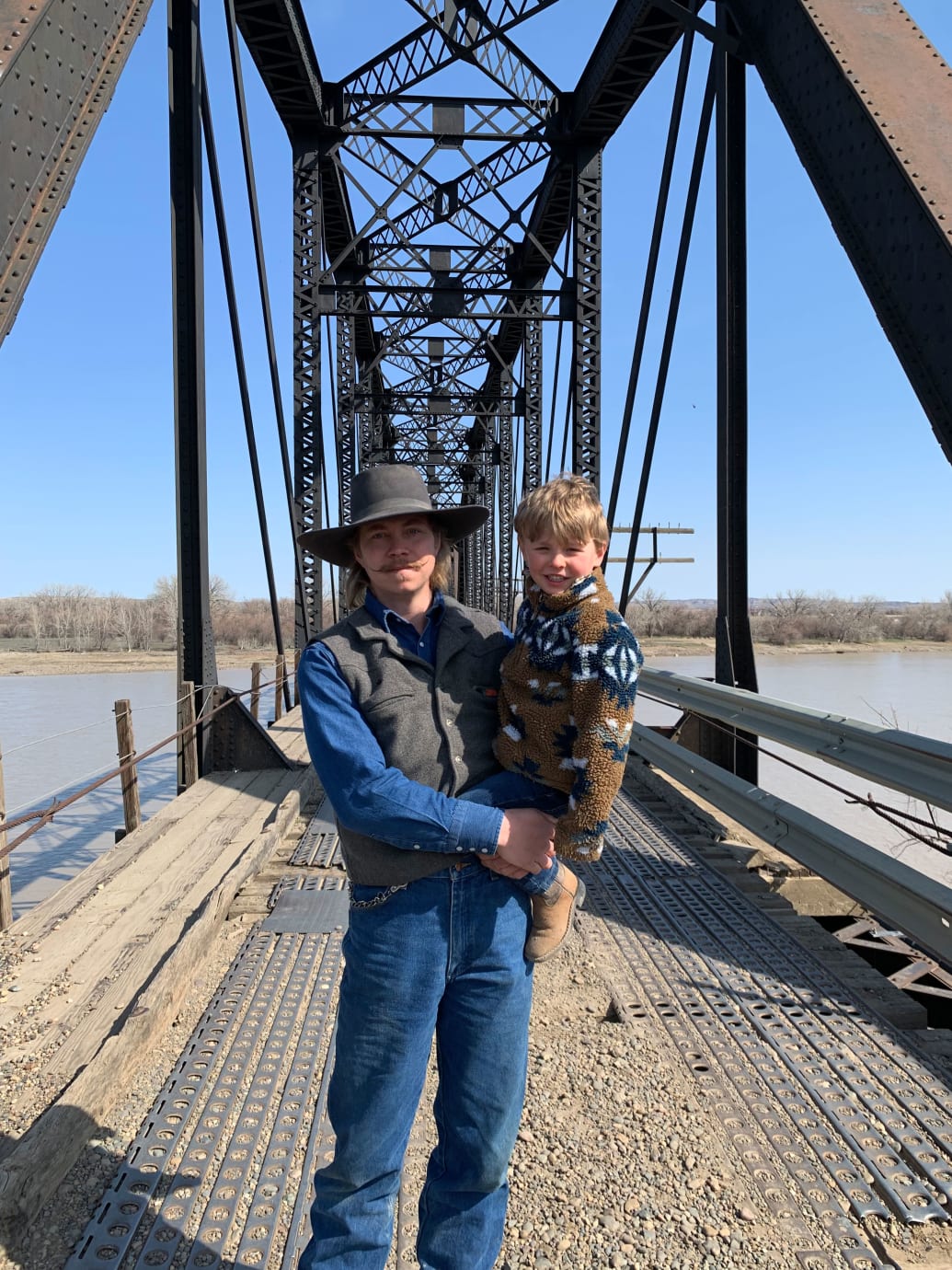 A picture of Isaac Carrier holding his son, Stetson, on a bridge