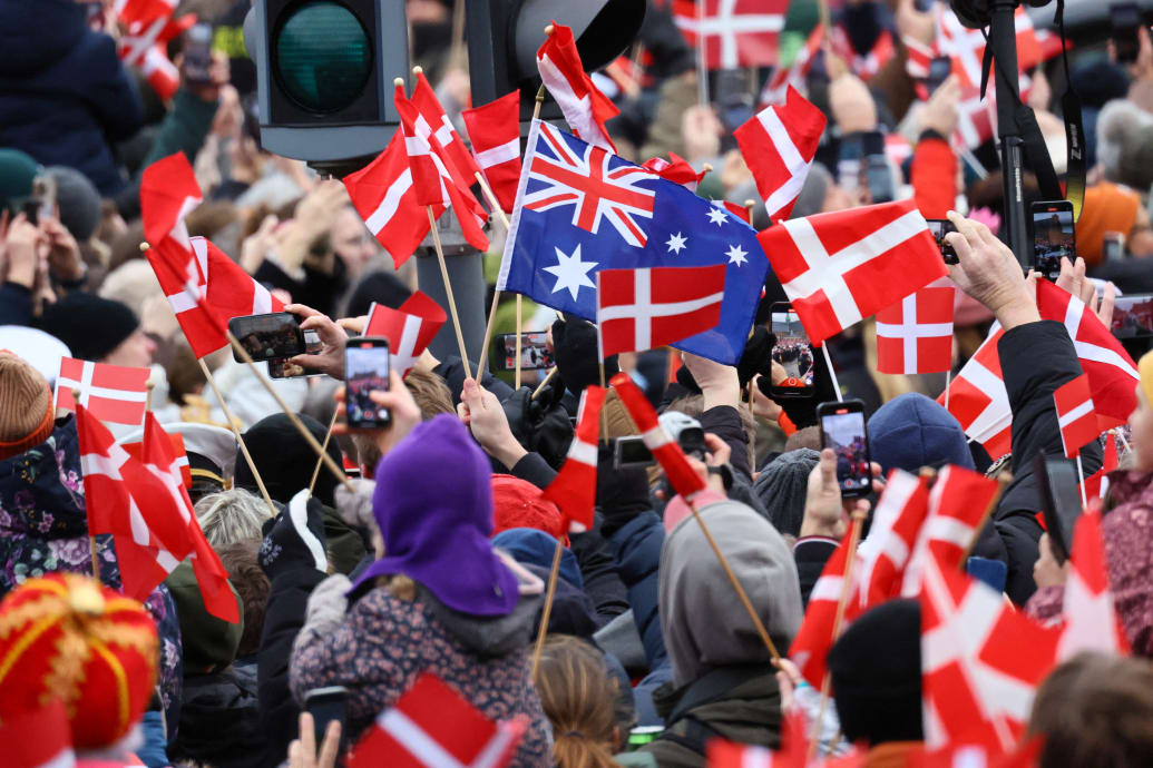 People hold flags as they gather on the day Danish Queen Margrethe abdicates after 52 years on the throne, and her elder son, Crown Prince Frederik, ascends the throne as King Frederik X, in Copenhagen, Denmark, January 14, 2024.