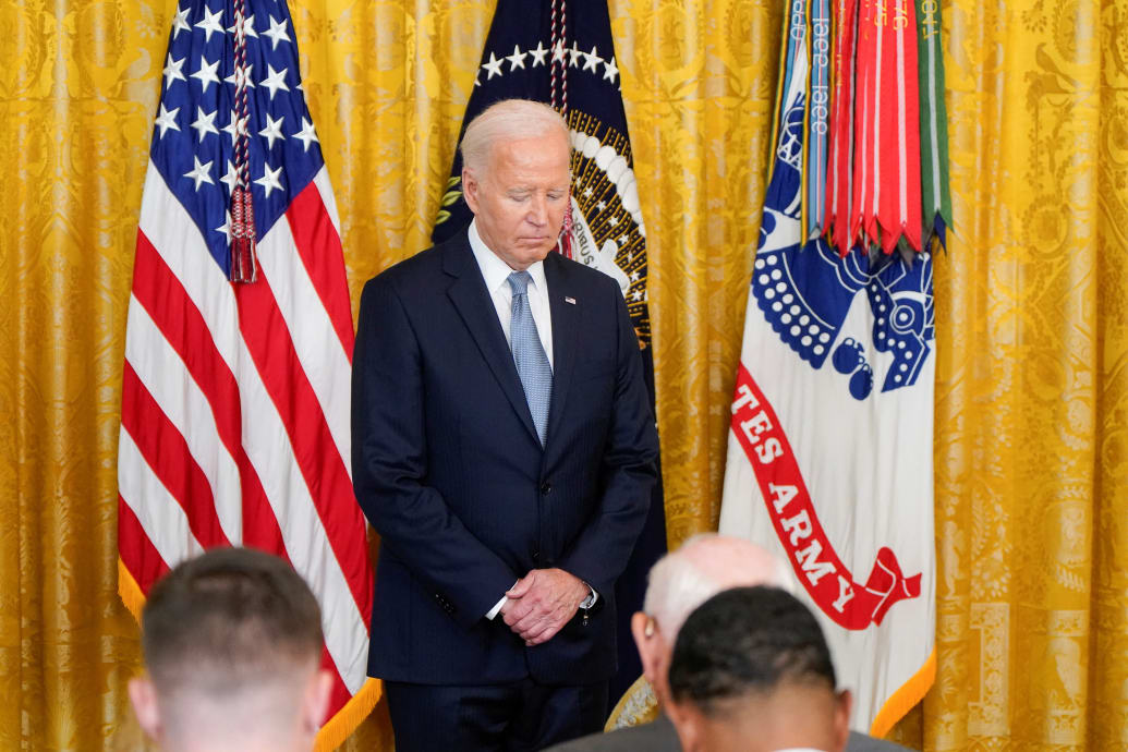 Joe Biden in front of flags head bowed