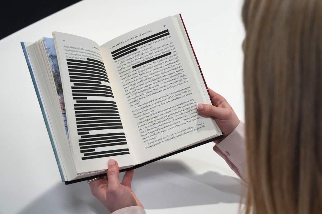 A woman reading a copy of Rebel Rising by Rebel Wilson, the headline-making memoir has been published in the UK with allegations about the actor Sacha Baron Cohen redacted for legal reasons.