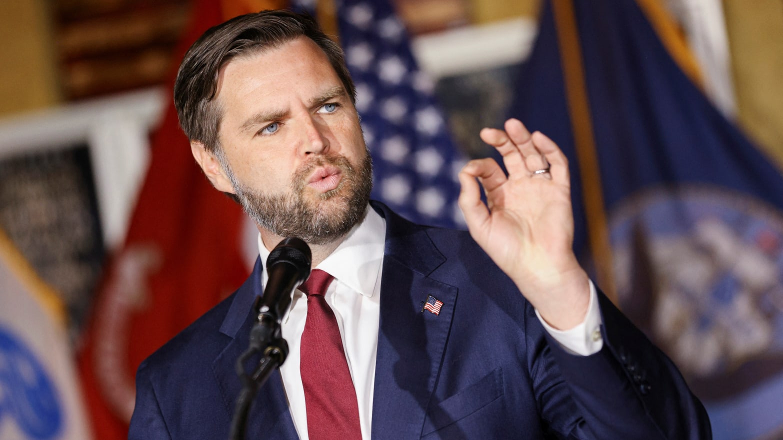 JD Vance raises his left hand while speaking at a campaign event.