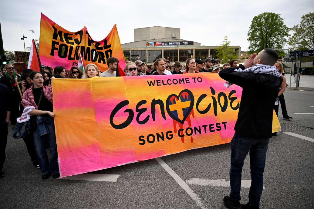 Protesters march carrying sign that says "Welcome to Genocide Song Contest"