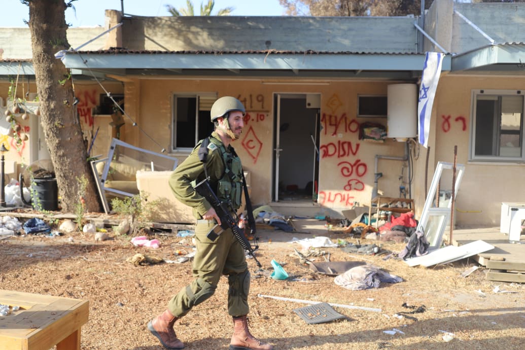 A photo of an Israeli soldier walking through Kibbutz Be'eri and Kibbutz Kfar.