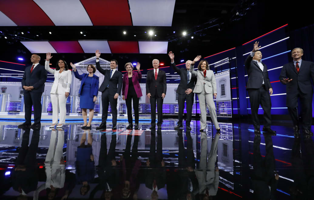 Democratic candidates at a 2019 presidential debate waving.