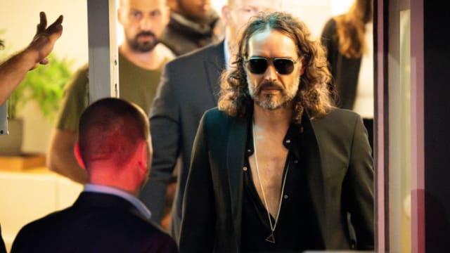 Russell Brand wears sunglasses as he walks out of a theatre in London.