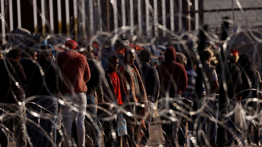 Migrants stand near the border wall after having crossed the U.S.-Mexico border as seen from Ciudad Juarez, Mexico, May 12, 2023.