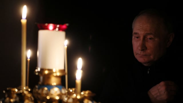 Russian President Vladimir Putin lights a candle.