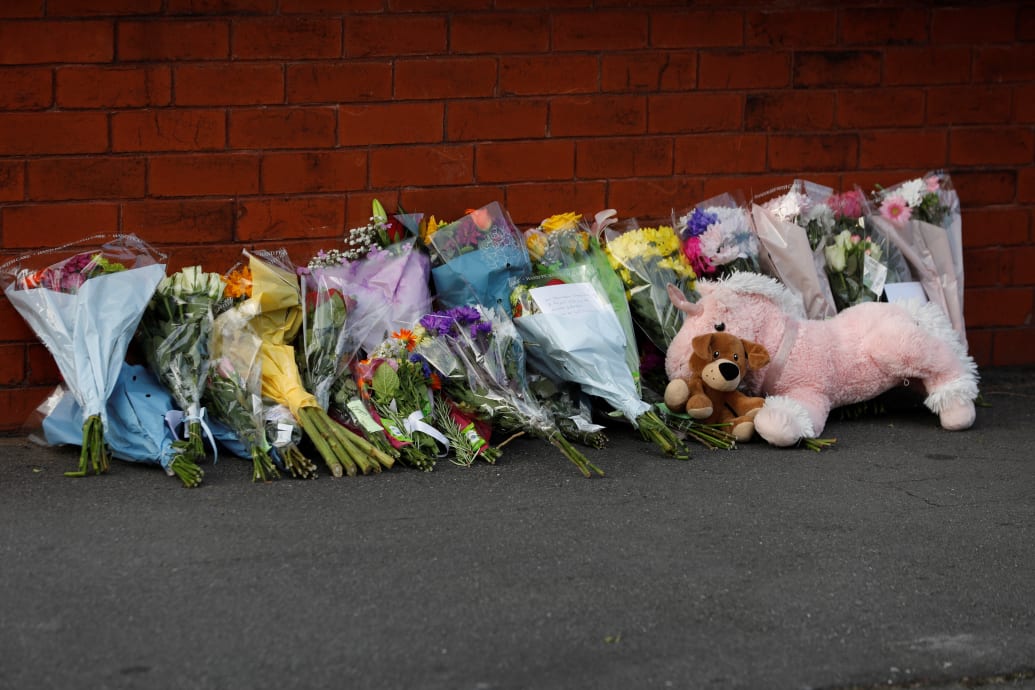 Flowers and a stuffed animal are seen behind the police cordon near the scene of a stabbing incident