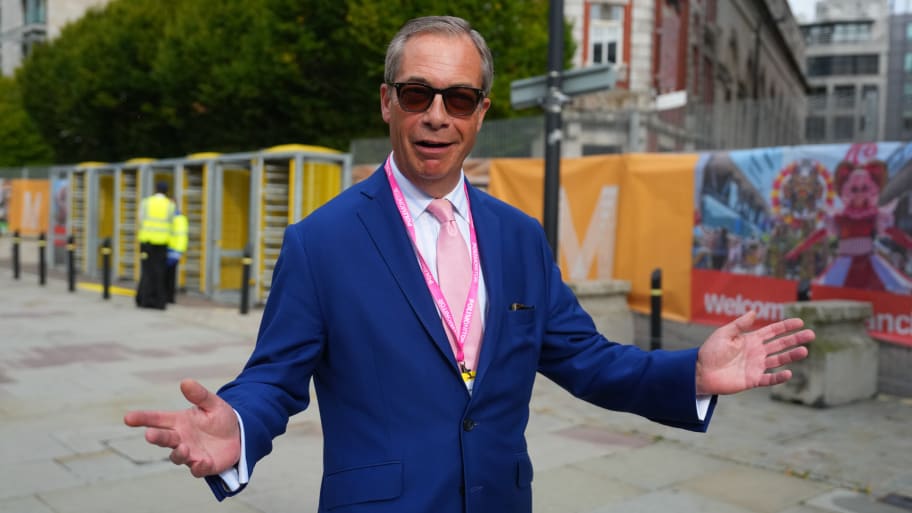 Nigel Farage standing outside with his arms spread open.