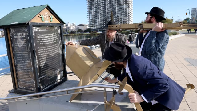 Rabbi Dovid Labkowski, and rabbis in training Moshe Turk and Mendy Stern, of the Chabad Jewish Center of Oakland, from left, place pieces of damaged menorah