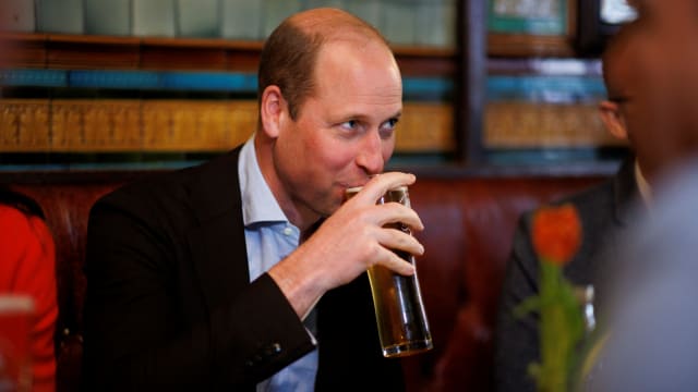 Britain's William, Prince of Wales drinks a pint of cider as he chats to local business people inside the Dog and Duck pub in Soho ahead of King Charles' coronation, in London, May 4, 2023.
