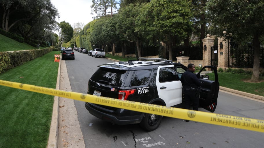 Police cars are seen behind caution tape outside the home of US producer and musician Sean "Diddy" Combs in Los Angeles