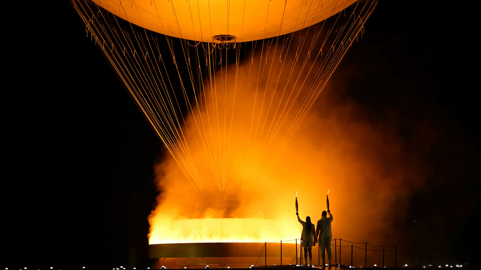 The torchbearers French former sprinter Marie-Jose Perec and French judoka Teddy Riner arrive to light the Olympic cauldron