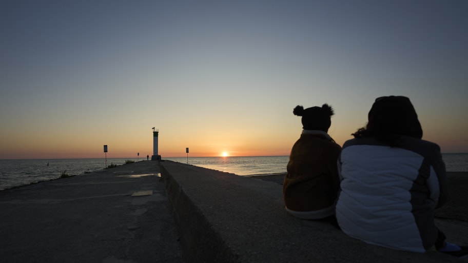 People gather near the pier in Grand Bend, Ontario, to watch the sunset over Lake Huron on May 12, 2024. 