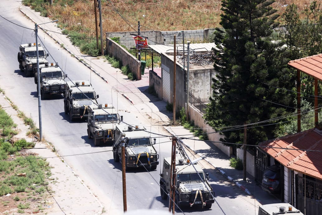 A photograph of six Israeli military armoured vehicles advancing on a road during a raid of Jenin city in the West Bank on July 3, 2023.