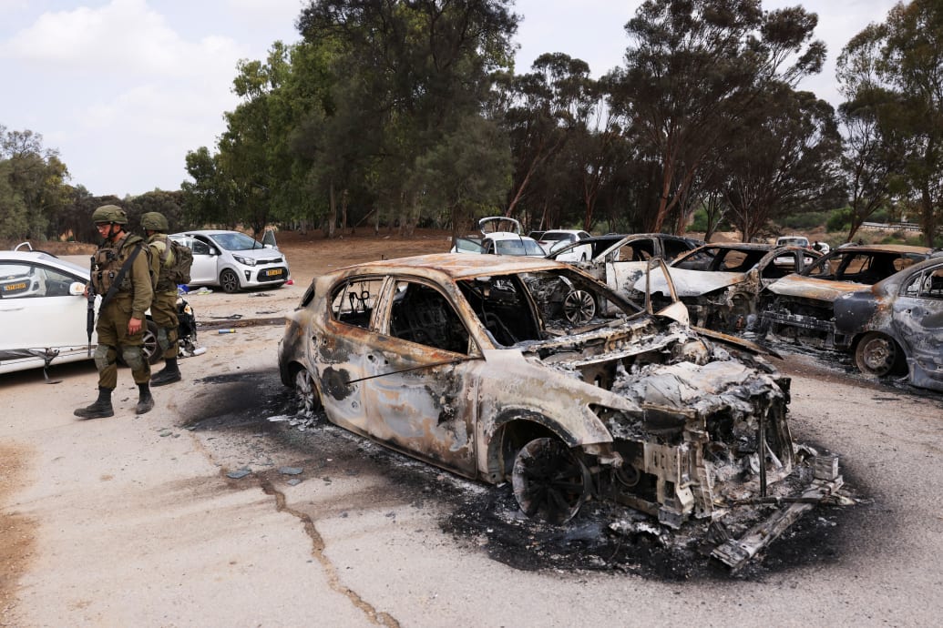 A photo of Israeli soldiers inspecting the charred remains of cars abandoned in a parking lot near last weekend’s Supernova Festival.