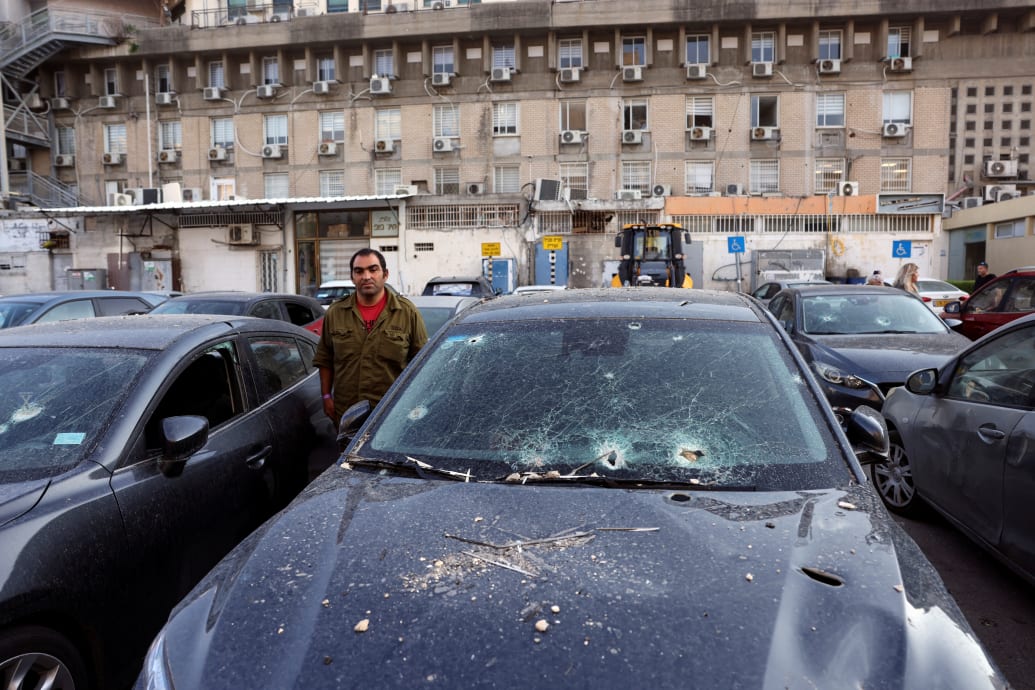 An Israeli soldier stands among cars damaged by rockets in Israel.