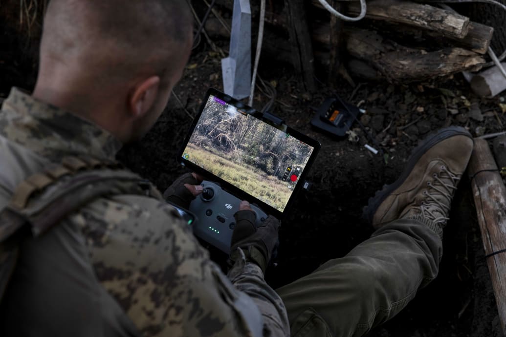  photograph of the head of an attack drone unit in the 68th Jaeger Brigade of the Ukrainian army rests a Starlink-connected phone on his body armor to communicate with other soldiers while piloting a drone in Luhansk region on September 1, 2023.