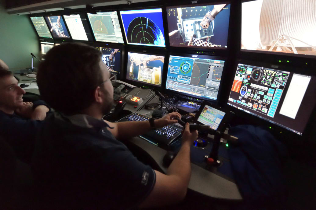 Workers survey a control room for the ROV (Remotely Operated underwater Vehicle) Victor 6000 during a previous observation mission.