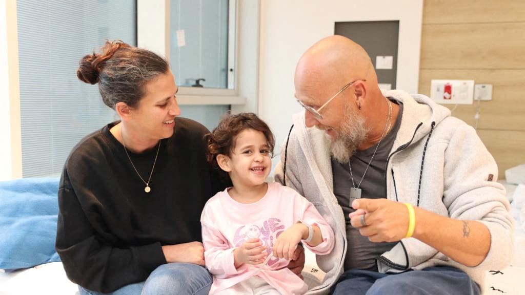 Abigail Edan smiles with loved ones inside a hospital room.
