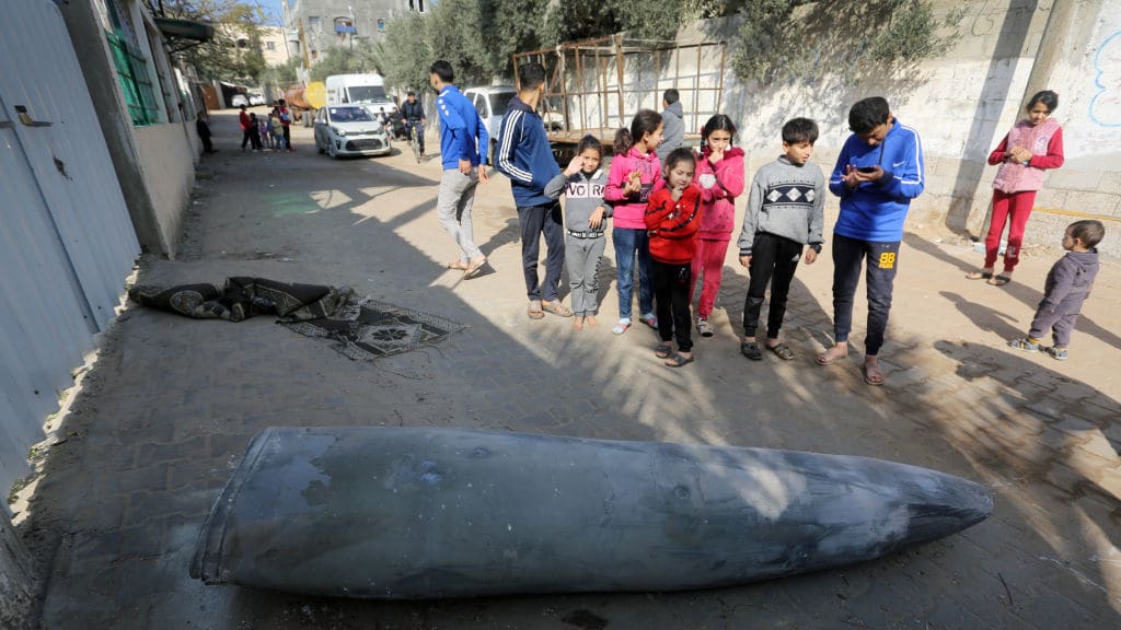 Children examine an unexploded rocket that fell on empty area between the buildings as Israeli attacks on Gaza continue in Deir Al Balah.