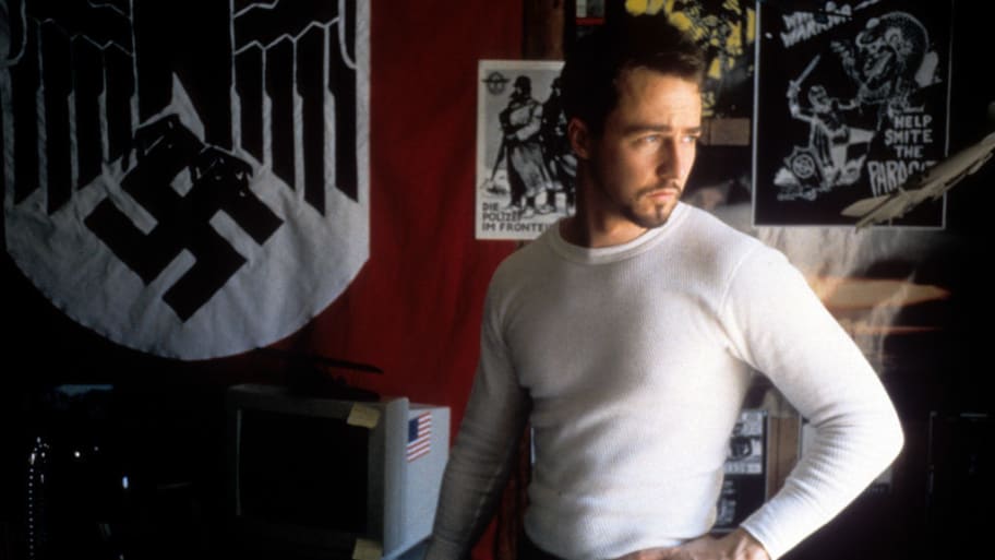 Edward Norton poses in front of a Nazi flag.