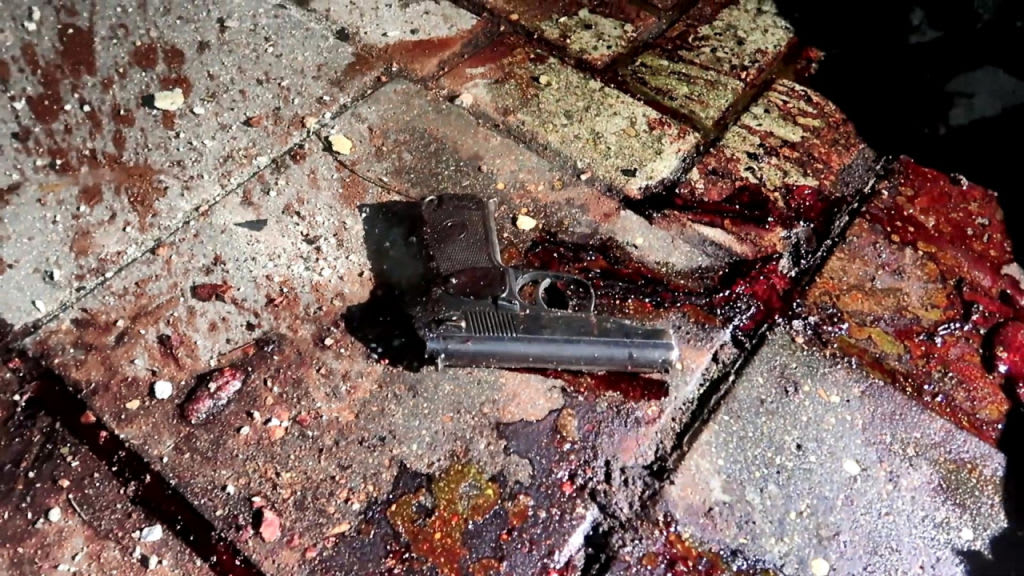 A gun lies in a pool of blood after more than 15 police officers were killed in a suspected terror attack in Dagestan, Russia.