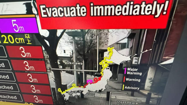 A warning message on a television screen asks people to evacuate immediately from an area after earthquakes hit Japan.