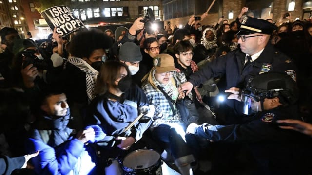 Protesters clash with a NYPD officer on the campus of NYU.