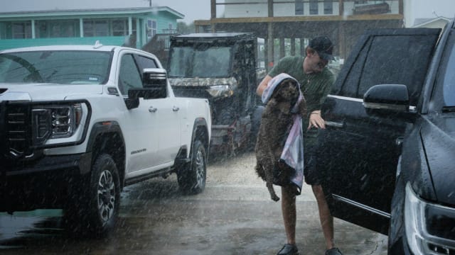 Black Braun loads his dog Dolly into his family’s vehicle as outer bands from Tropical Storm Beryl begin to hit Texas’ Gulf Coast.