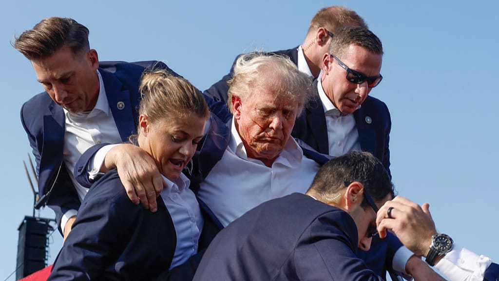 Donald Trump is swiftly escorted off stage by Secret Service agents after a 20-year-old gunman opened fire at him.