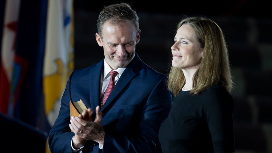 Jesse Barrett claps and looks down while standing next to a smiling Amy Coney Barrett.