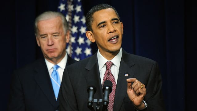 Then-President Barack Obama (R) speaks as Vice President Joe Biden looks on.