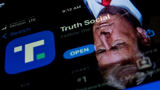 This photo illustration shows an image of former President Donald Trump reflected in a phone screen that is displaying the Truth Social app.