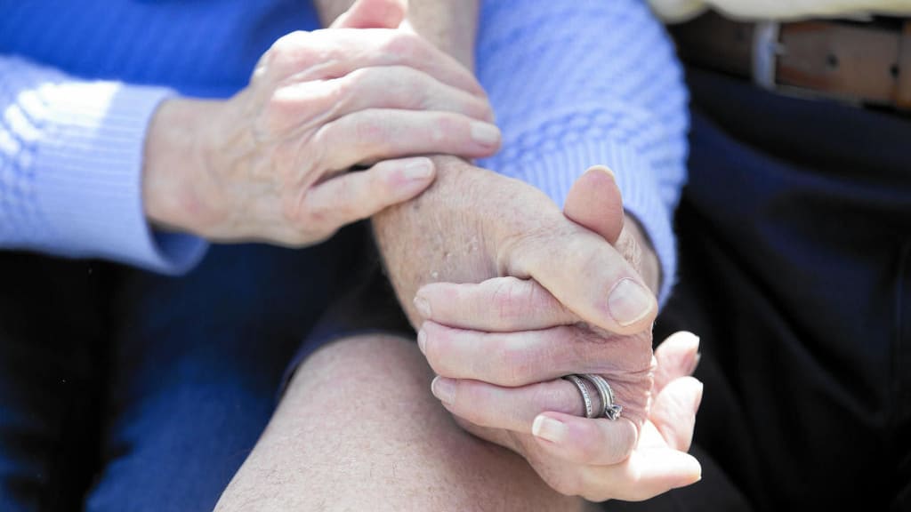 A pair of elderly people holding hands.