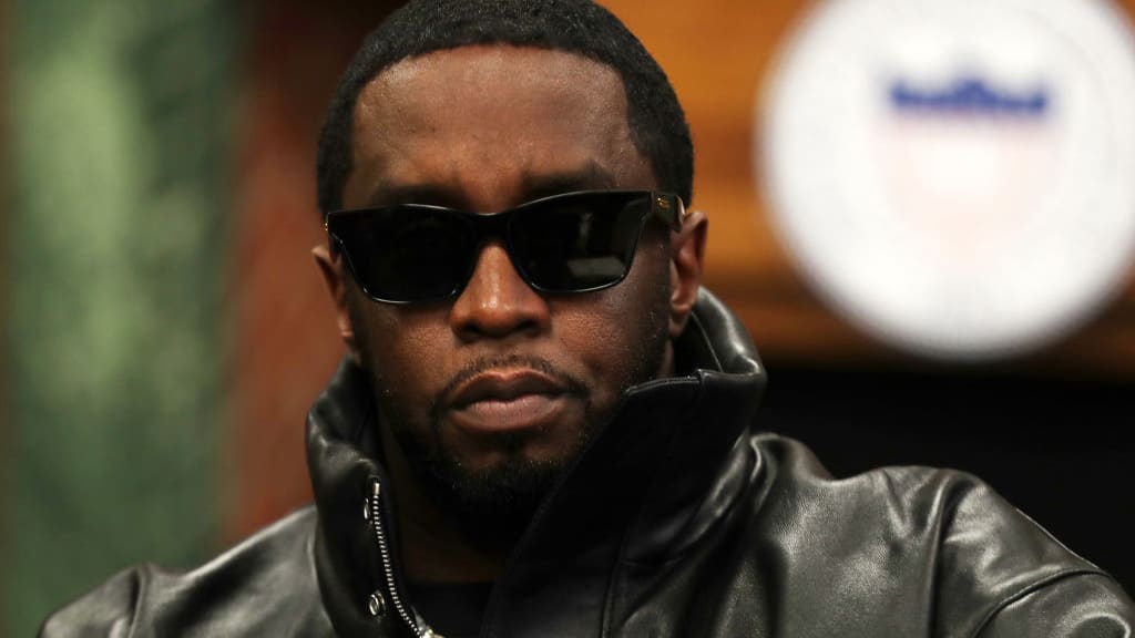 Sean Combs stares forward, wearing a leather jacket and glasses.