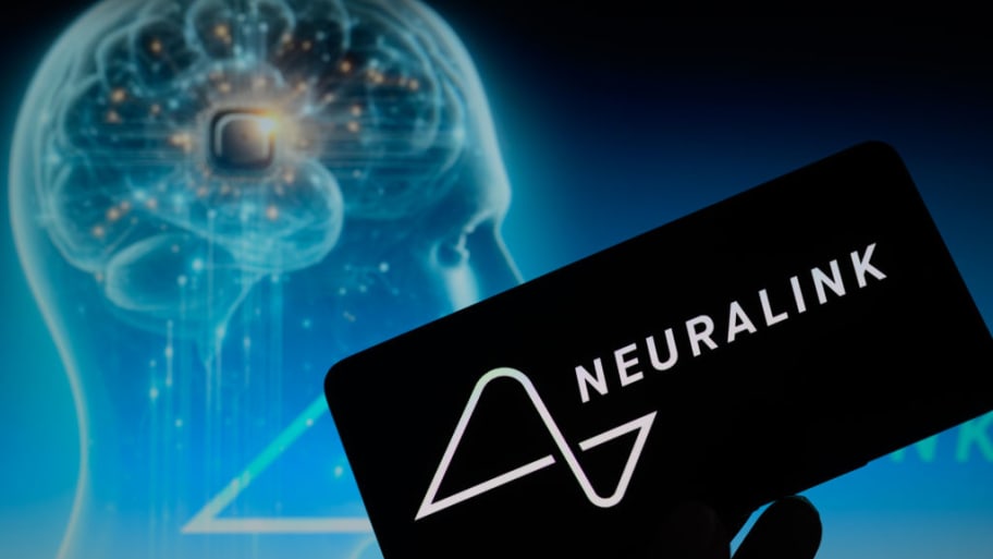 The Neuralink logo is being displayed on a smartphone with a brain chip visible in the background.