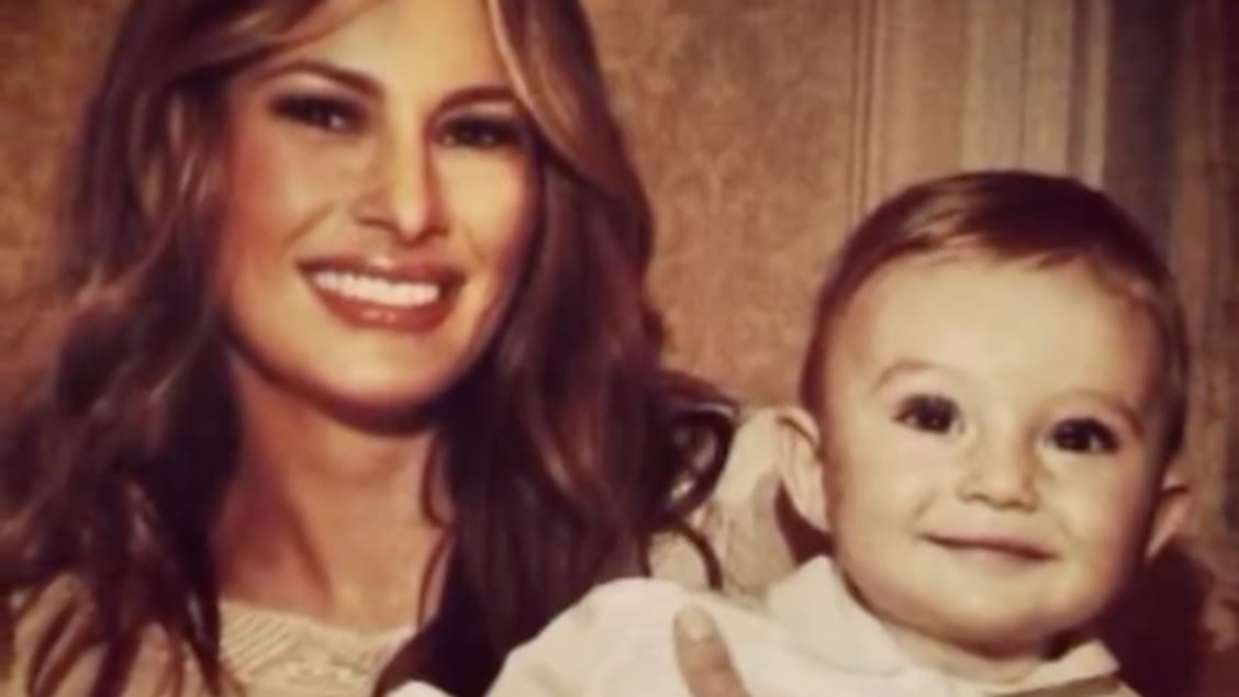 Melania Trump smiles as she holds an infant-aged Barron Trump, her now-18-year-old son.