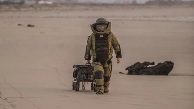 A bomb squad member removes an explosive from a California beach