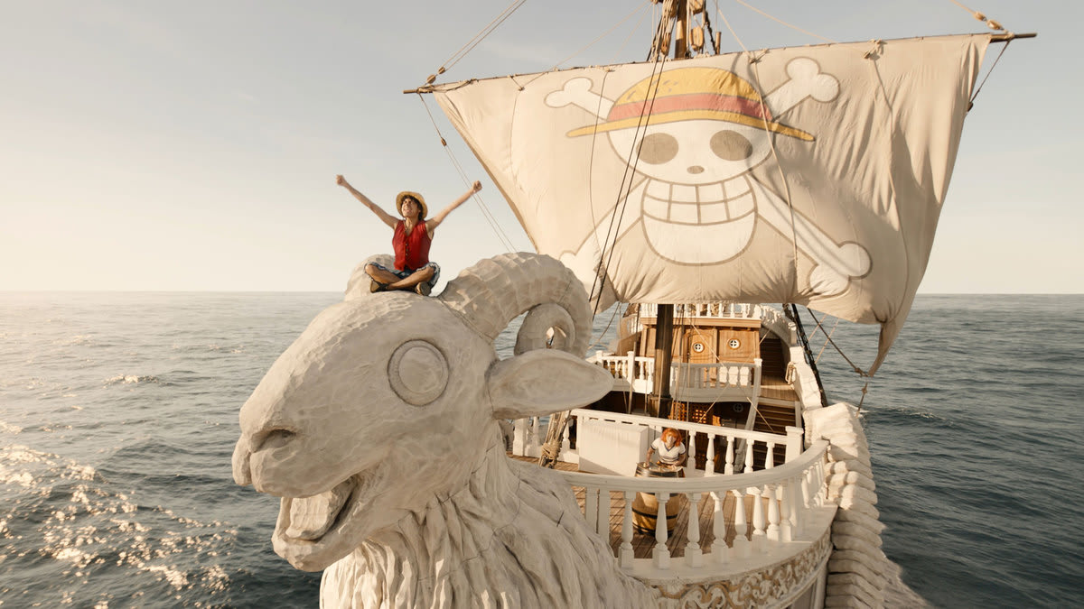 Luffy sits on the helm of a large white pirate ship.