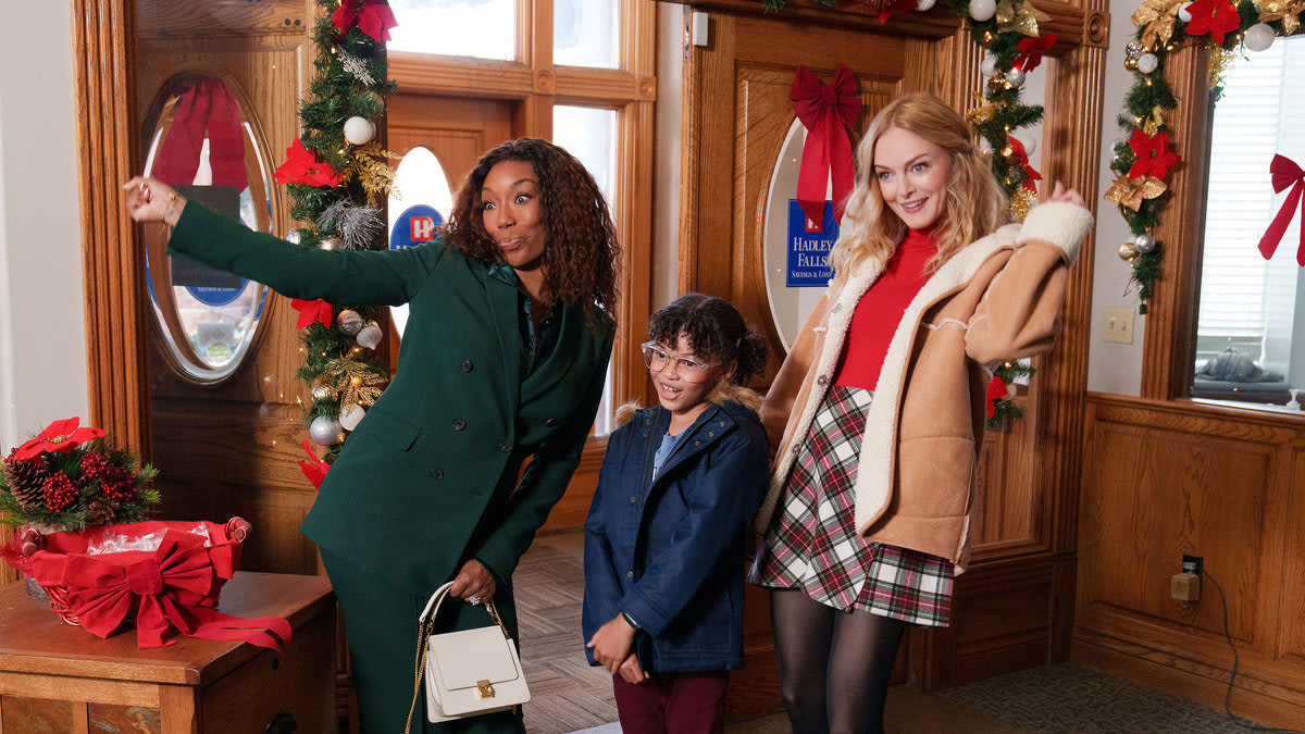 Brandy Norwood, Madison Validum and Heather Graham stand next to each other in the doorway in winter coats in a still from Netflix’s Best Christmas Ever